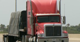 red flatbed truck with black tarp cover