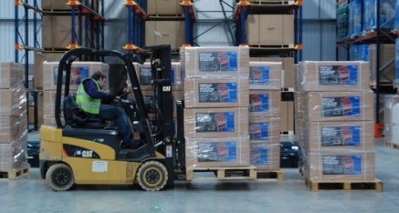 man lifting boxes in warehouse with forklift